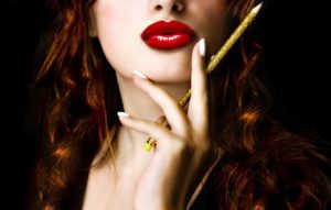 A sexy woman with red lip gloss holding a pencil seductively.